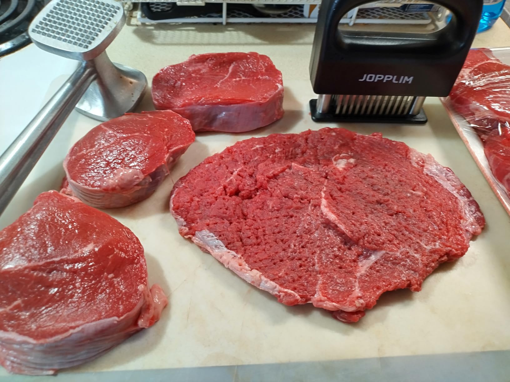 Tenderized steak with blade marks on cutting board