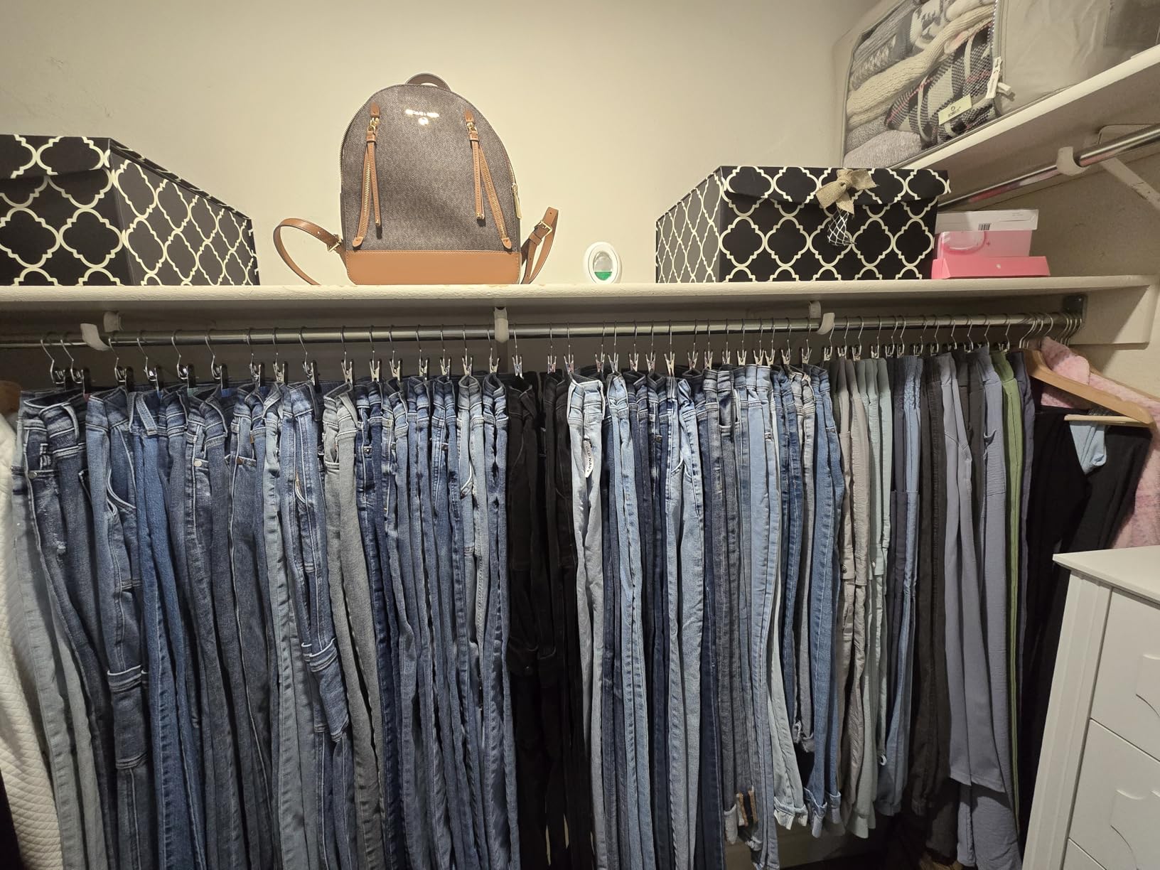Full closet organized with many jeans hanging on clip hangers