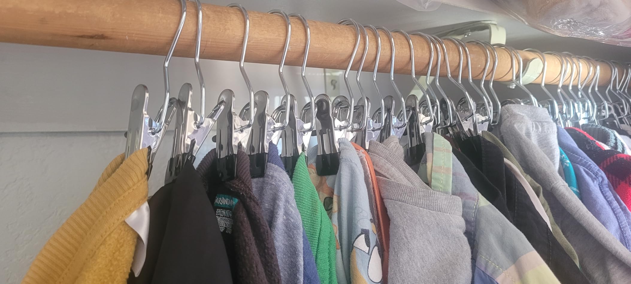 Colorful clothes hanging on closet rod with clip hangers