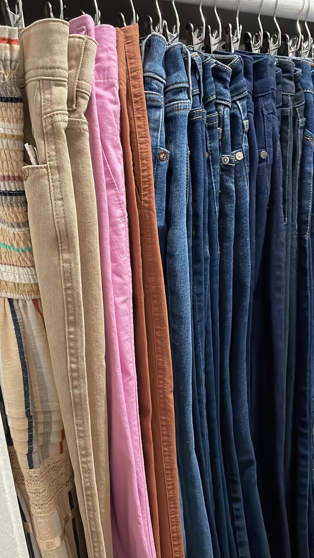Pants and jeans hanging closely with metal clip hangers